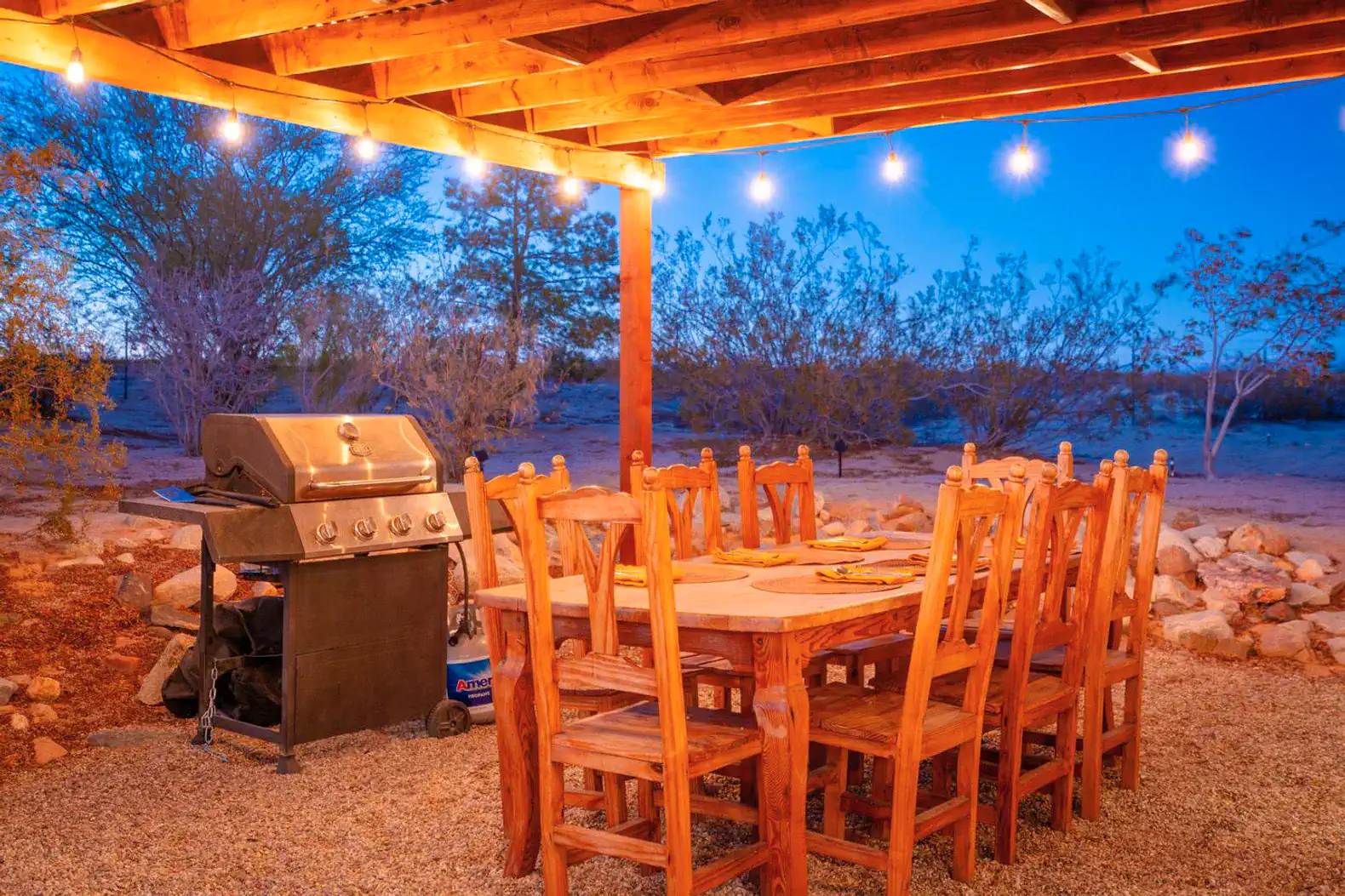 Outdoor dining area with a large wooden table and grill under a covered patio