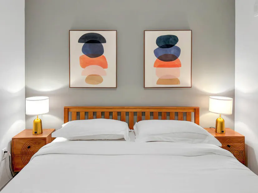 Gemütliches Schlafzimmer mit moderner Kunst, Holzbettrahmen und Nachttischlampen