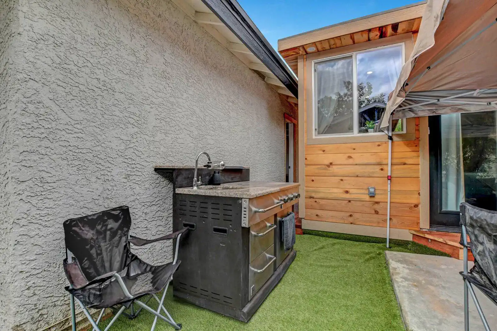 Outdoor area featuring a BBQ grill and seating on artificial grass