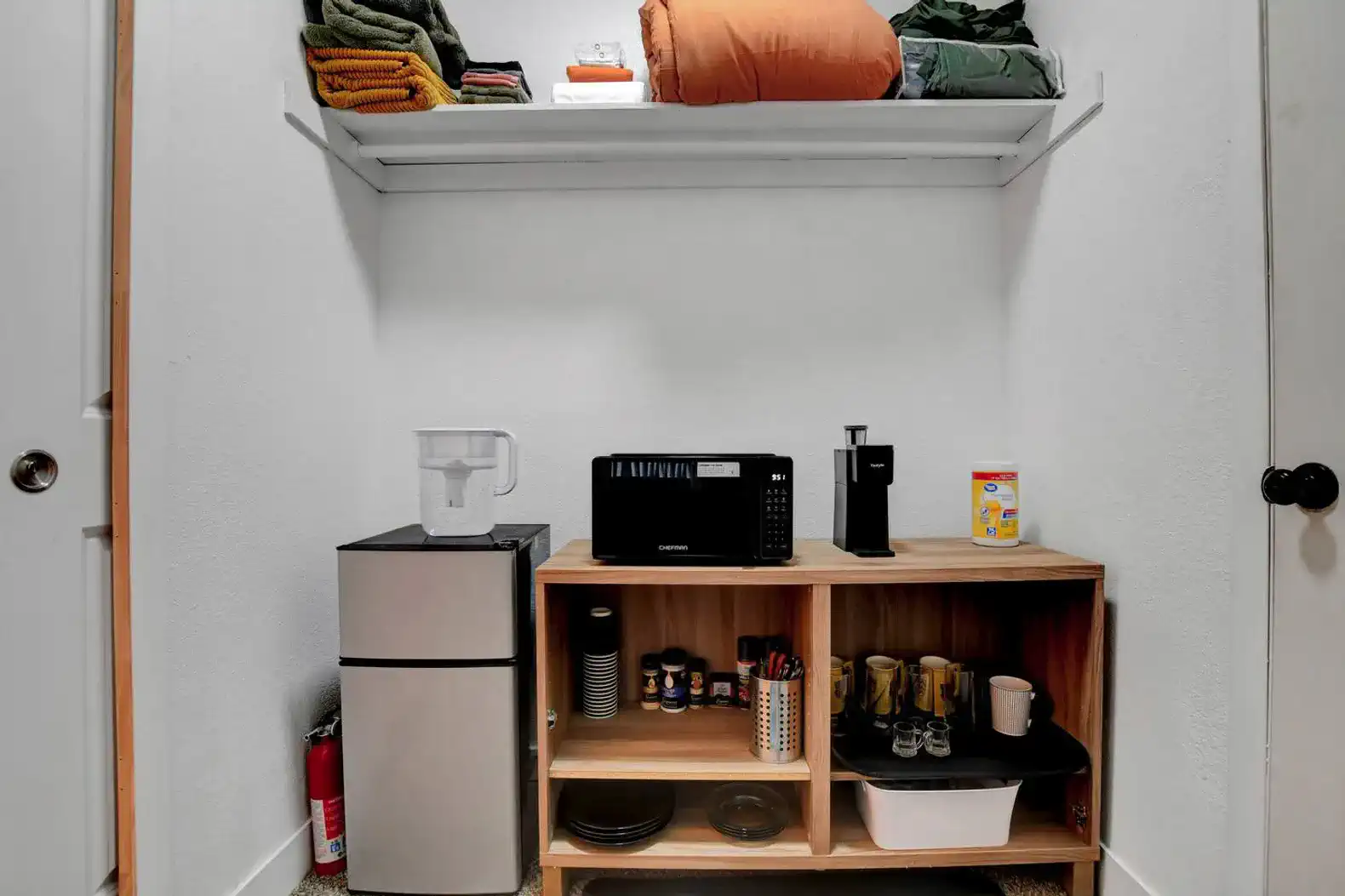 Storage area with shelves, mini fridge, microwave, and kitchen supplies