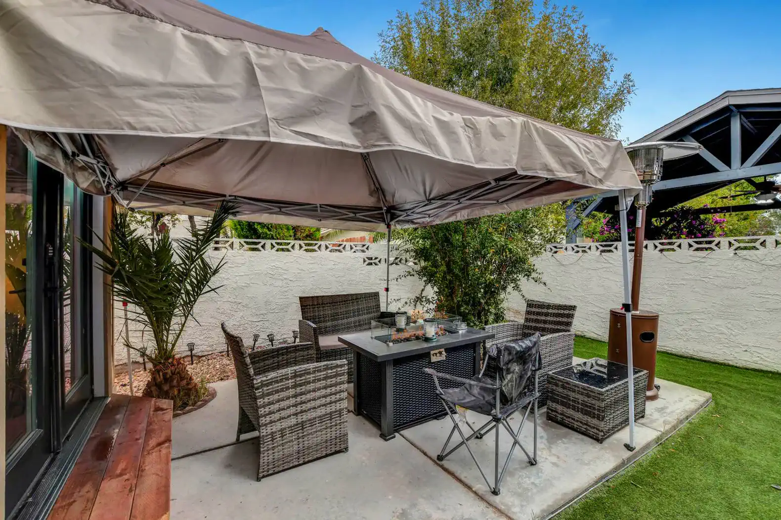 Covered outdoor dining area with seating and greenery