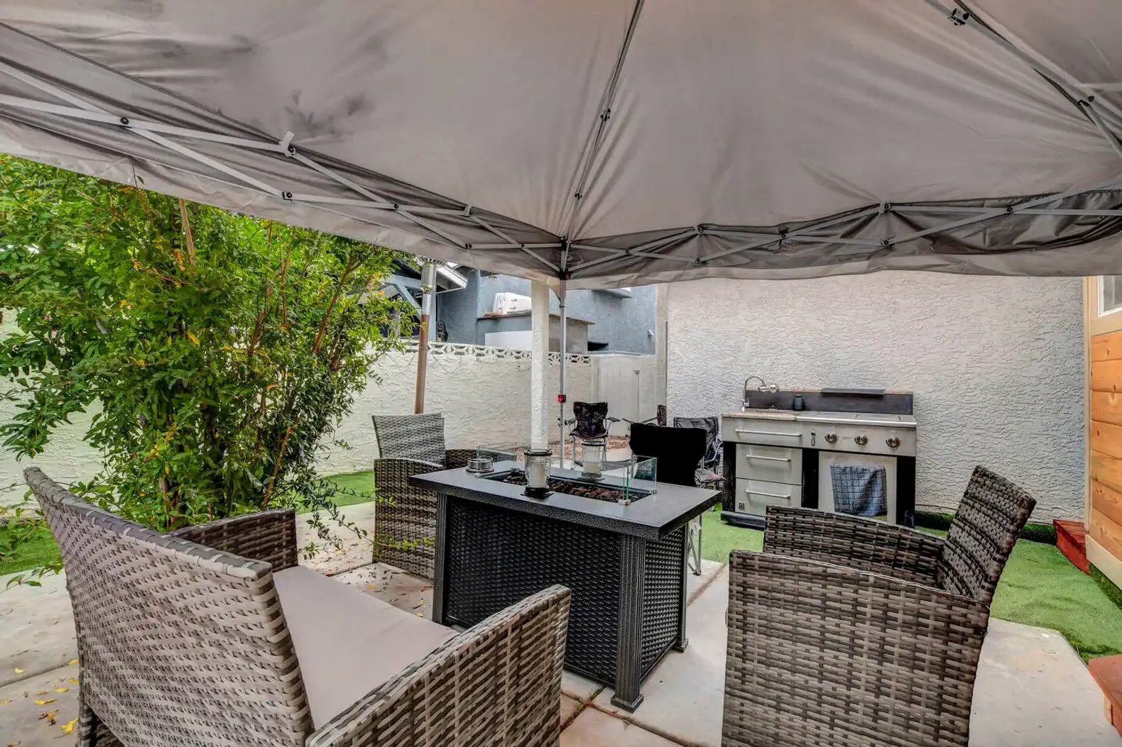 Cozy outdoor seating area with a fire pit and BBQ grill under a canopy
