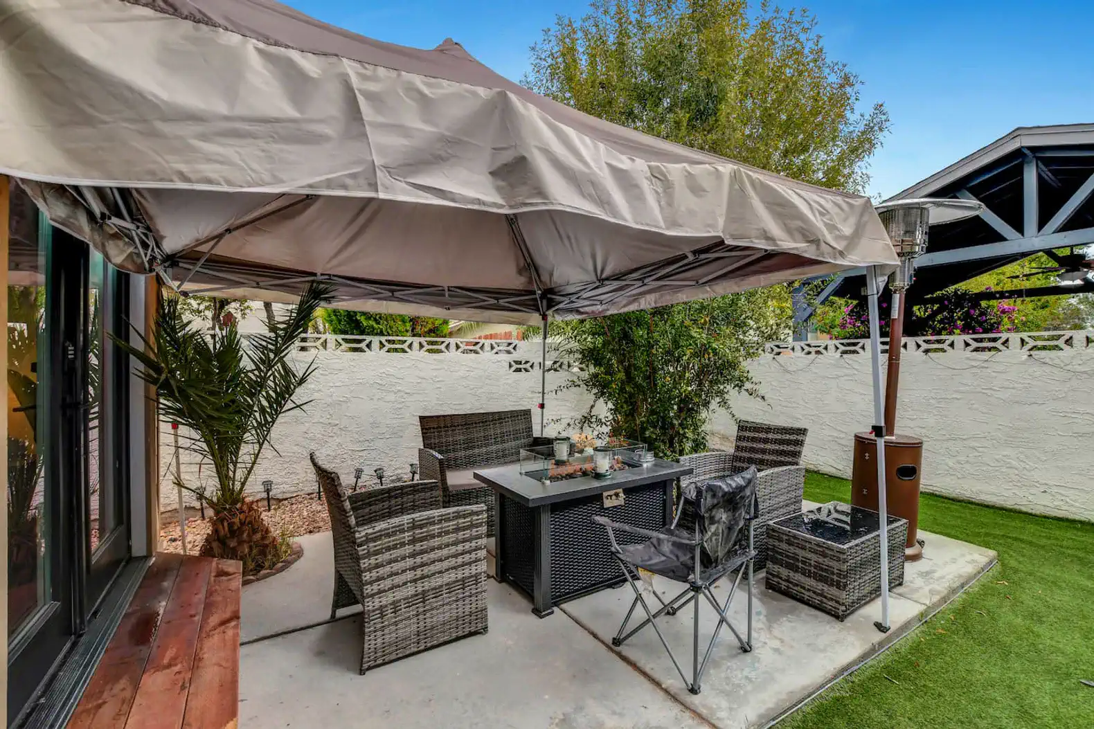 Covered outdoor dining area with seating and greenery