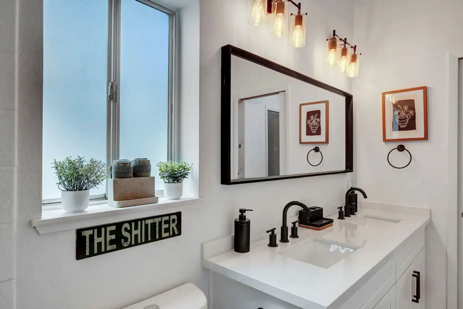 Modern bathroom with dual sinks, stylish lighting, and window view