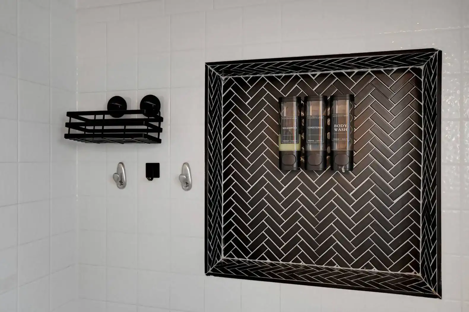 Stylish shower with herringbone tile design and built-in storage for toiletries