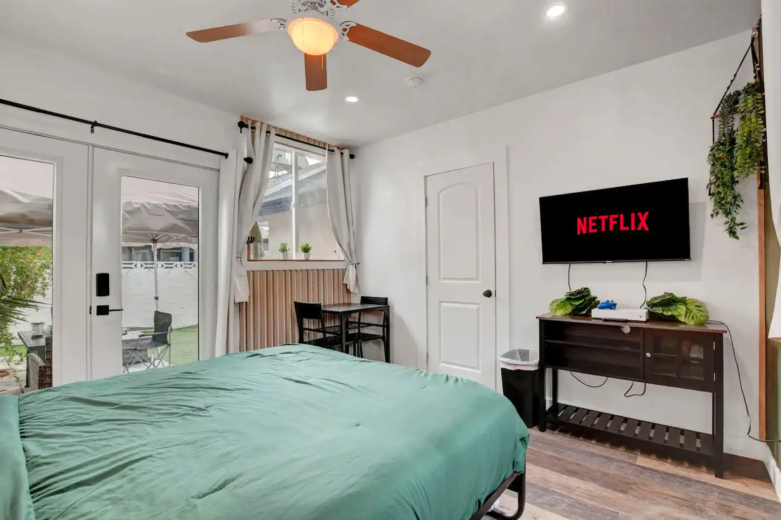Cozy bedroom with a green bedspread, TV, and access to the backyard