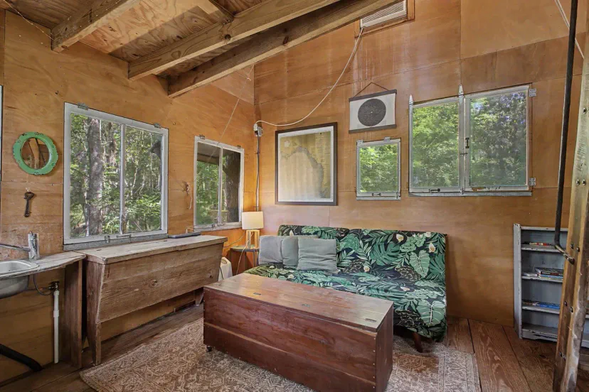 Gemütlicher Wohnbereich mit einem tropisch gestalteten Sofa und großen Fenstern mit Blick auf die Bäume