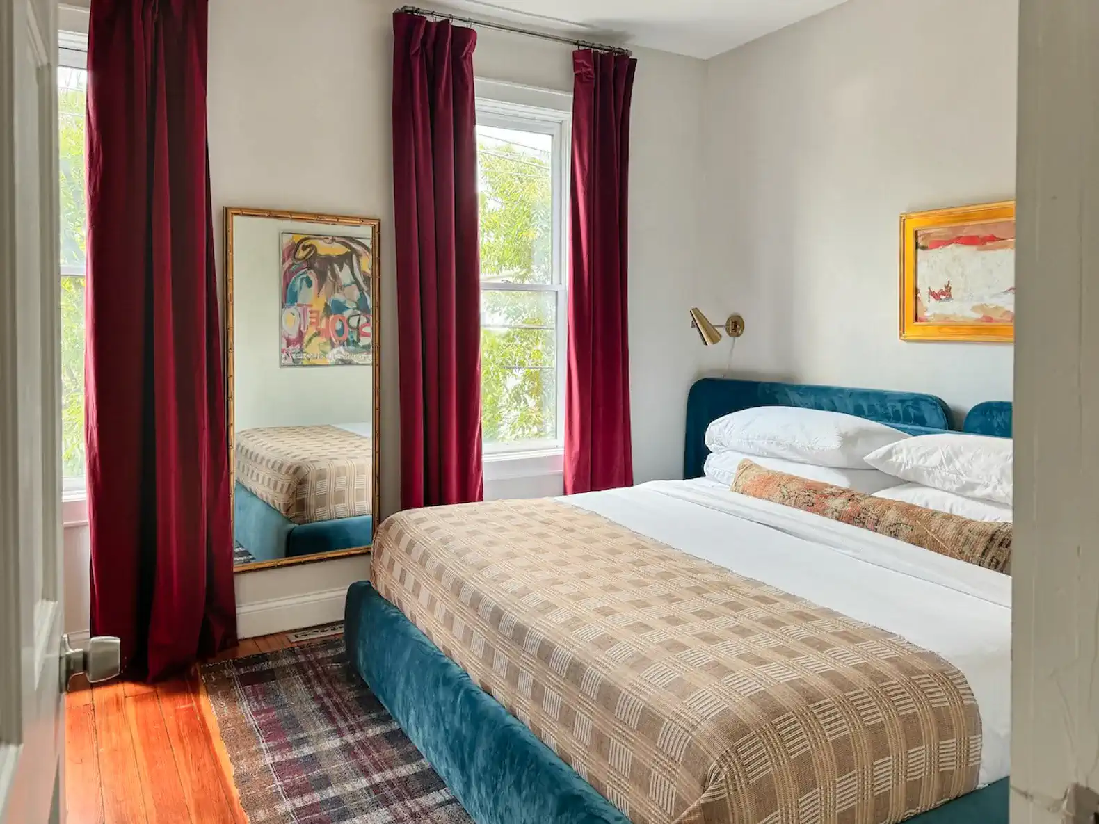 Cozy master bedroom with a blue bed, red curtains, and a large mirror