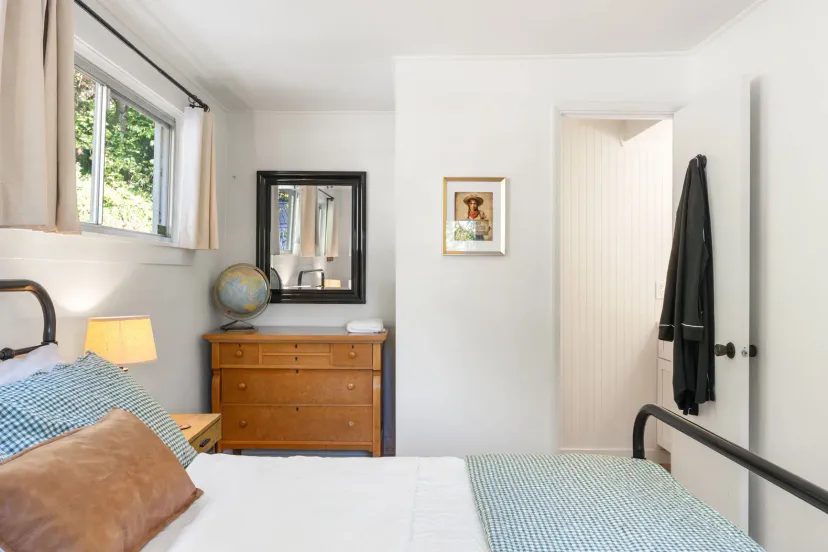 Cozy bedroom with a double bed, wooden dresser, globe, and natural light from large windows