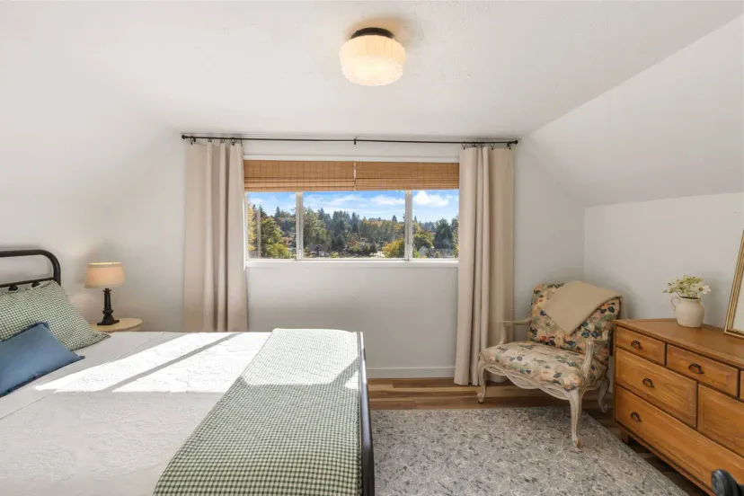 Cozy bedroom with a queen bed, large window showcasing scenic views, and charming vintage furnishings