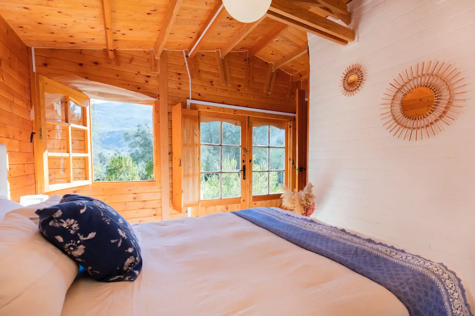 Cozy bedroom with wooden walls, large windows, and a comfortable bed