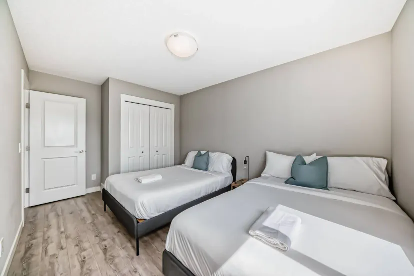 Helles Schlafzimmer mit zwei Betten, minimalistischer Dekoration und reichlich natürlichem Licht durch das Fenster
