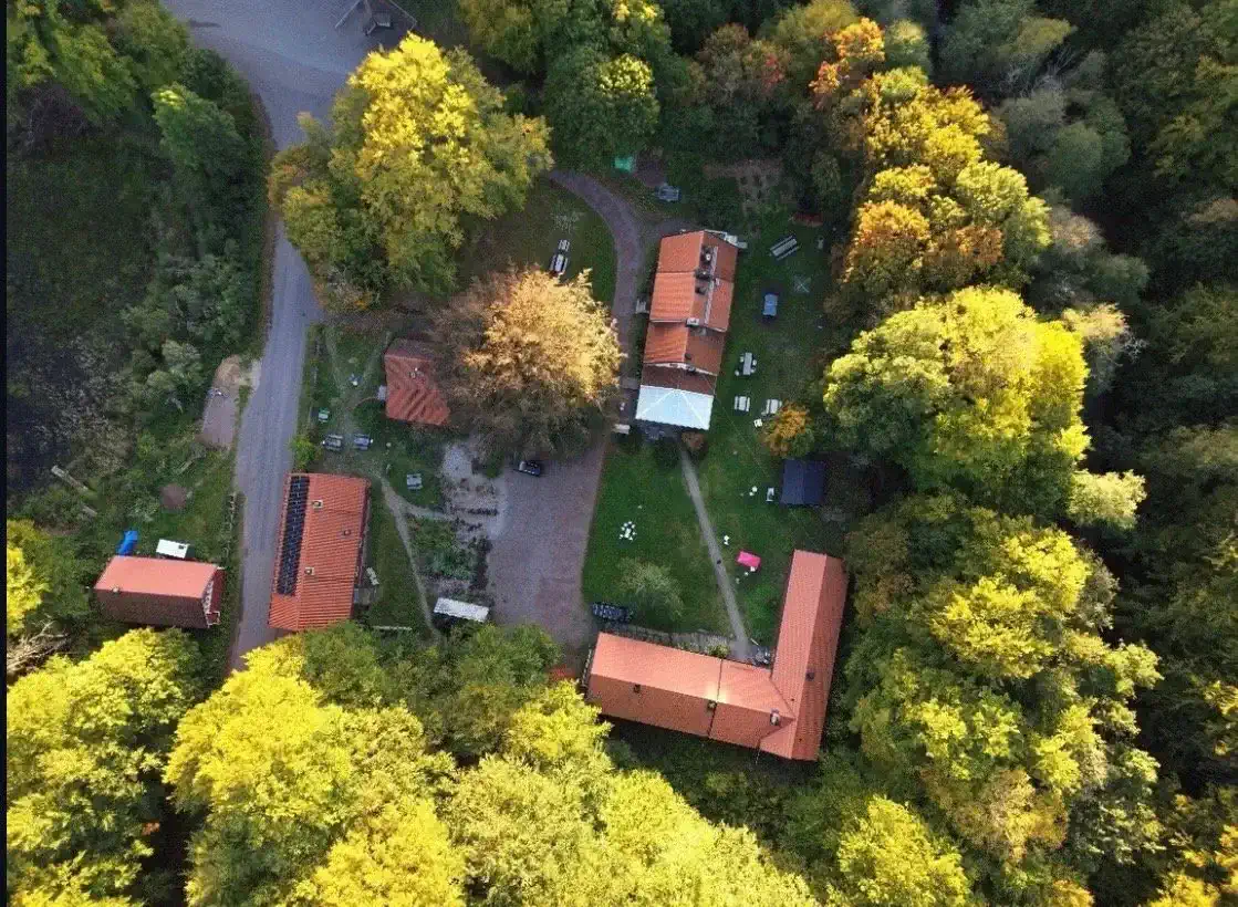 Aerial view of a property surrounded by lush trees and greenery with multiple buildings and outdoor spaces
