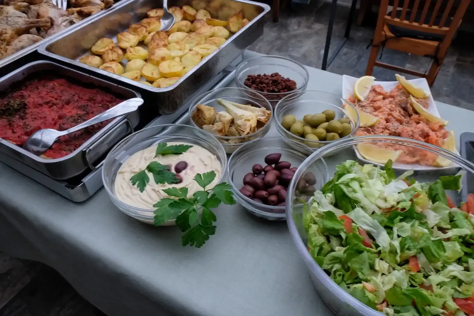 Eine Auswahl verschiedener Gerichte, darunter geröstete Kartoffeln, Salat, Hummus, Oliven und Meeresfrüchte