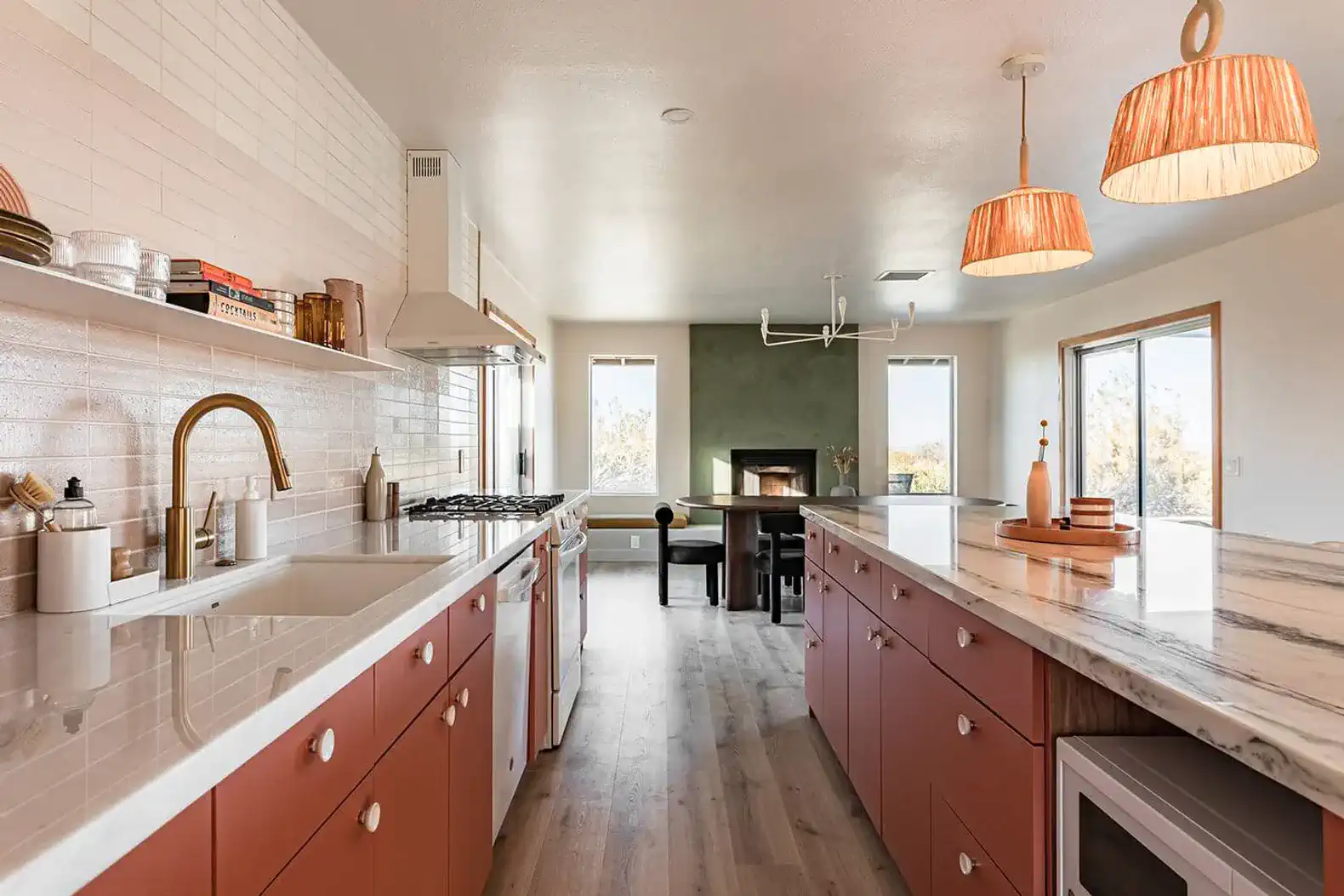 Modern kitchen with marble countertops, pink cabinetry, and a cozy dining area