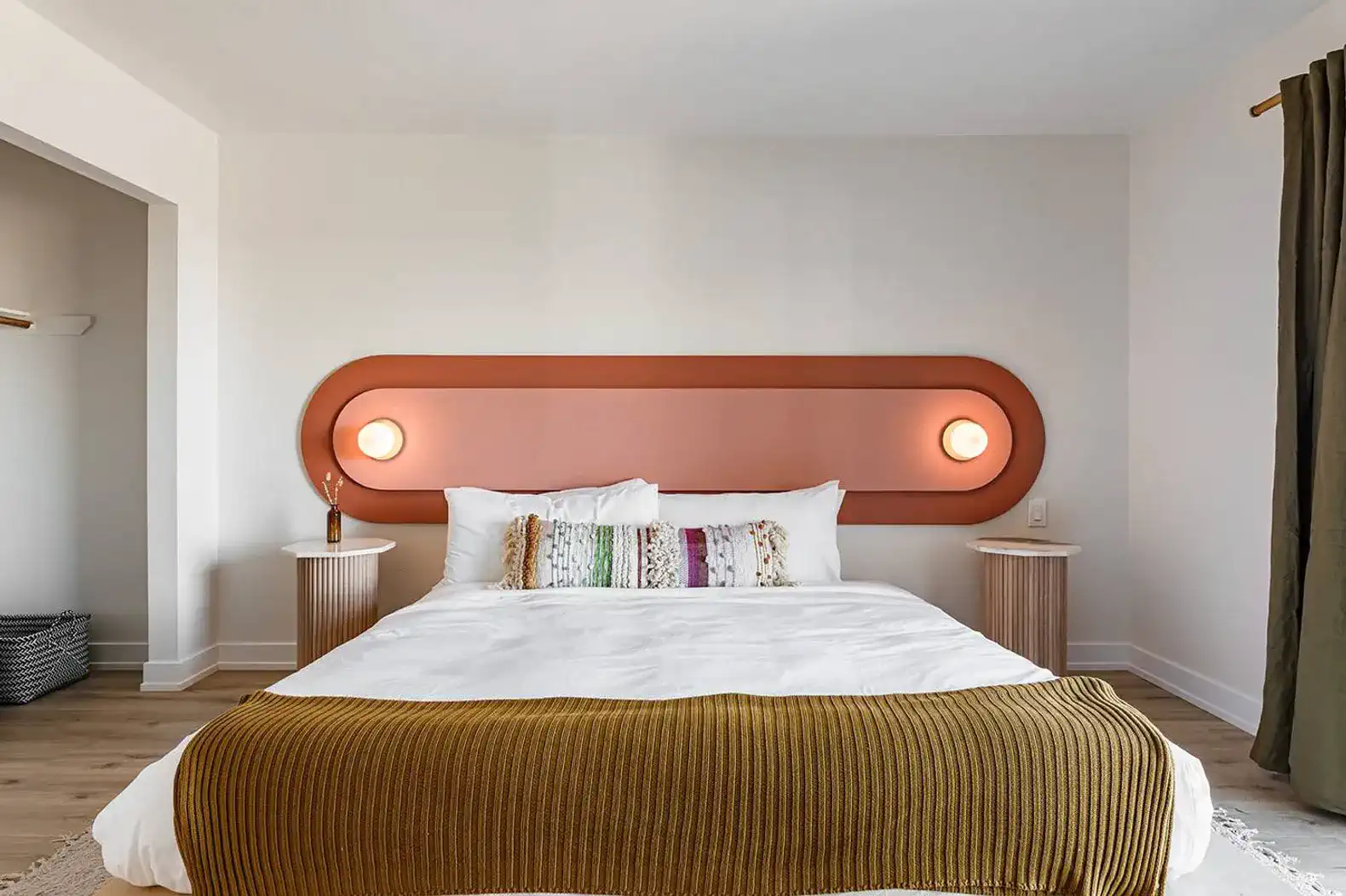 Stylish master bedroom with a large bed, modern lighting, and colorful accent wall