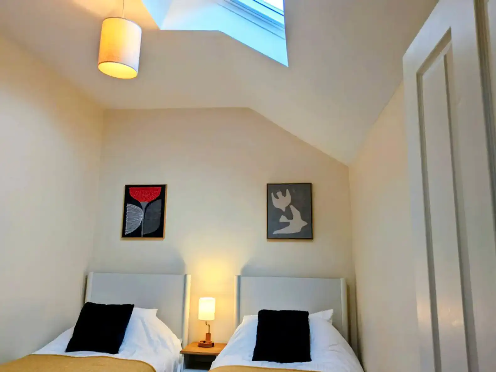 Cozy guest bedroom with two twin beds and skylight