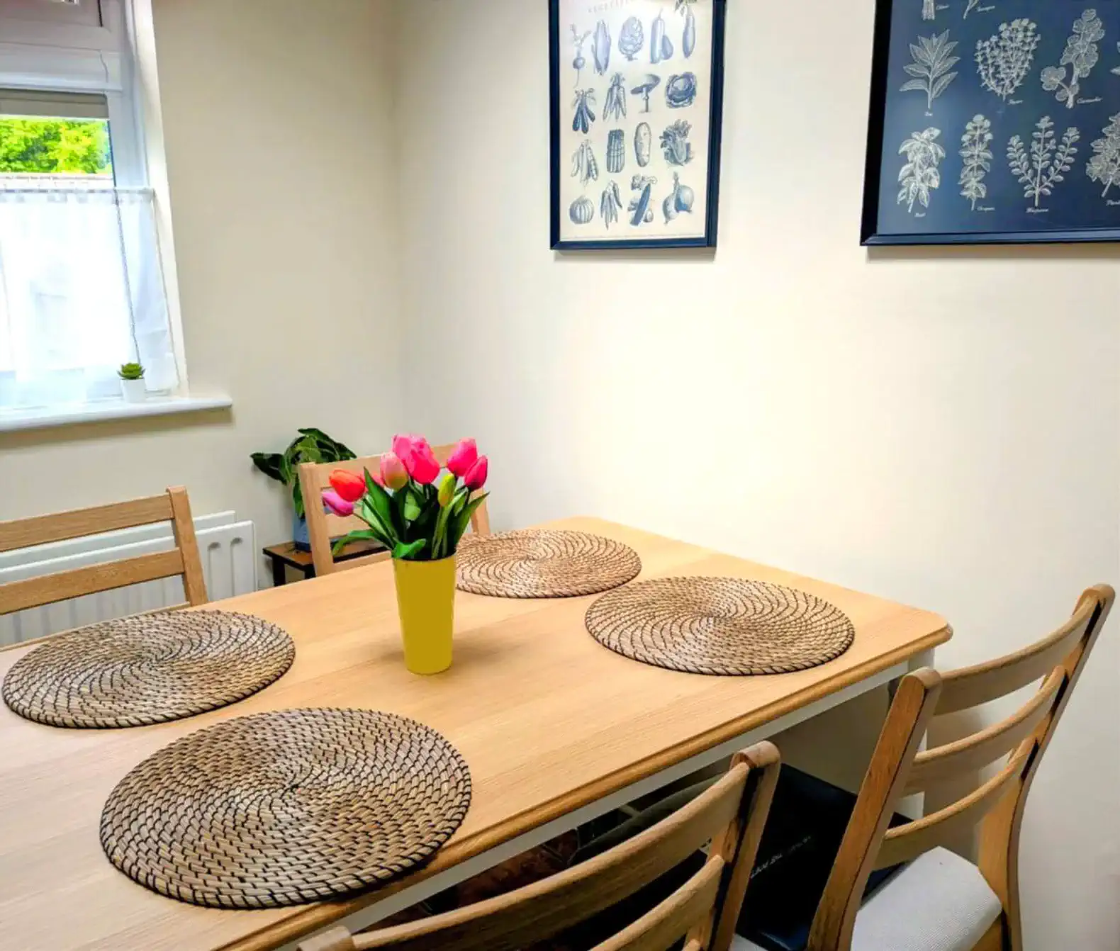 Bright dining area with a wooden table, floral centerpiece, and decorative wall art