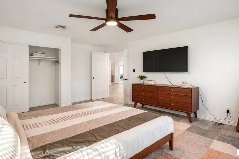 Spacious master bedroom with a comfortable bed, modern decor, and a flat-screen TV