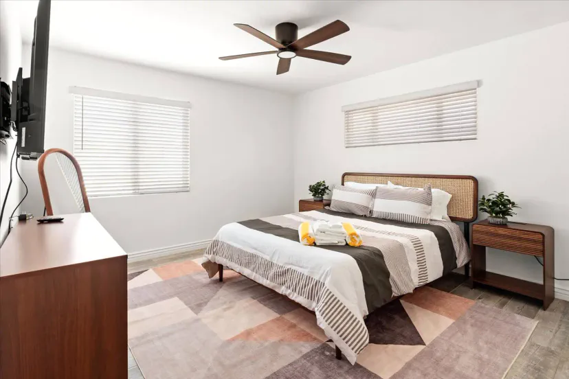 Gemütliches Hauptschlafzimmer mit einem Queensize-Bett, modernem Dekor und natürlichem Licht von den Fenstern