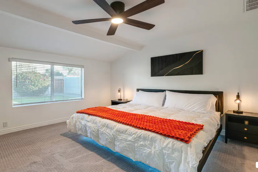 Spacious master bedroom with a king bed, modern decor, and natural light from a large window