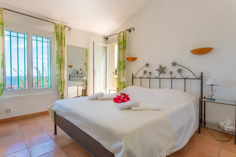 Bright bedroom with a double bed, green curtains, and a view of the garden through glass doors