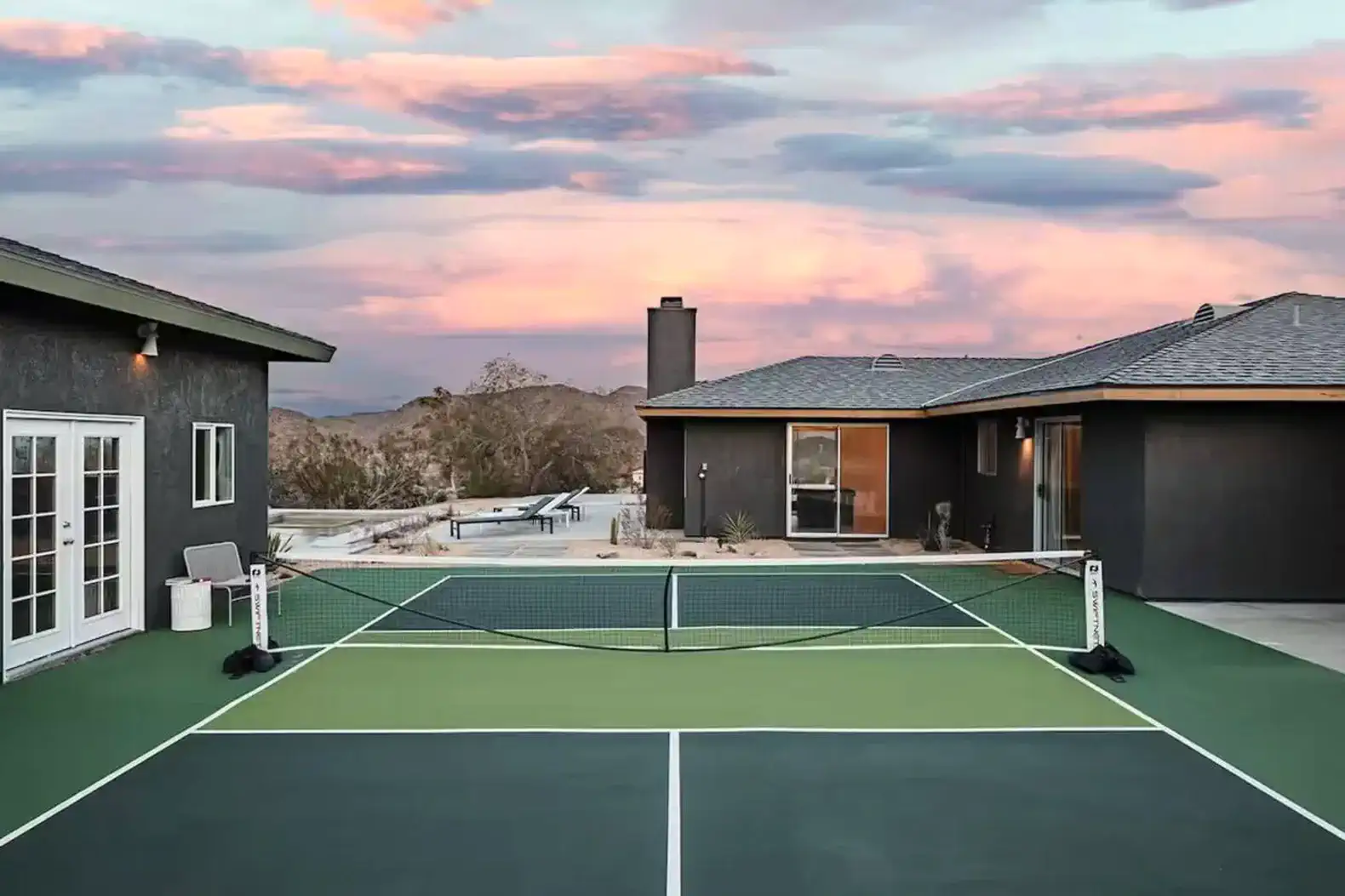 Tennis court with a scenic view of mountains and colorful sunset