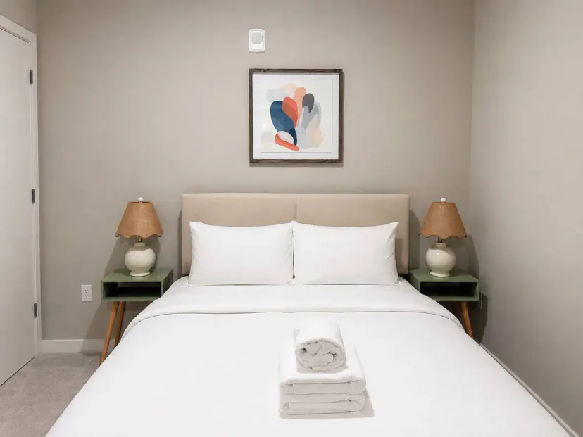 Gemütliches Hauptschlafzimmer mit einem bequemen Bett, Nachttischlampen und moderner Kunst