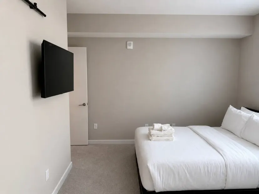 Quarto principal aconchegante com uma cama queen e TV montada na parede
