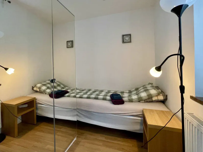 Quarto de hóspedes aconchegante com uma cama de solteiro, mesas de cabeceira de madeira e um espelho