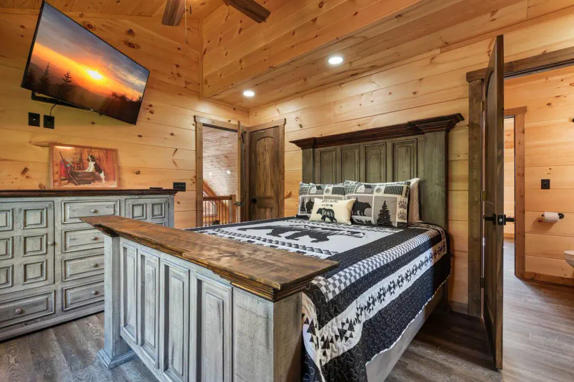 Cozy master bedroom with wooden walls, a large bed, and a TV mounted on the wall