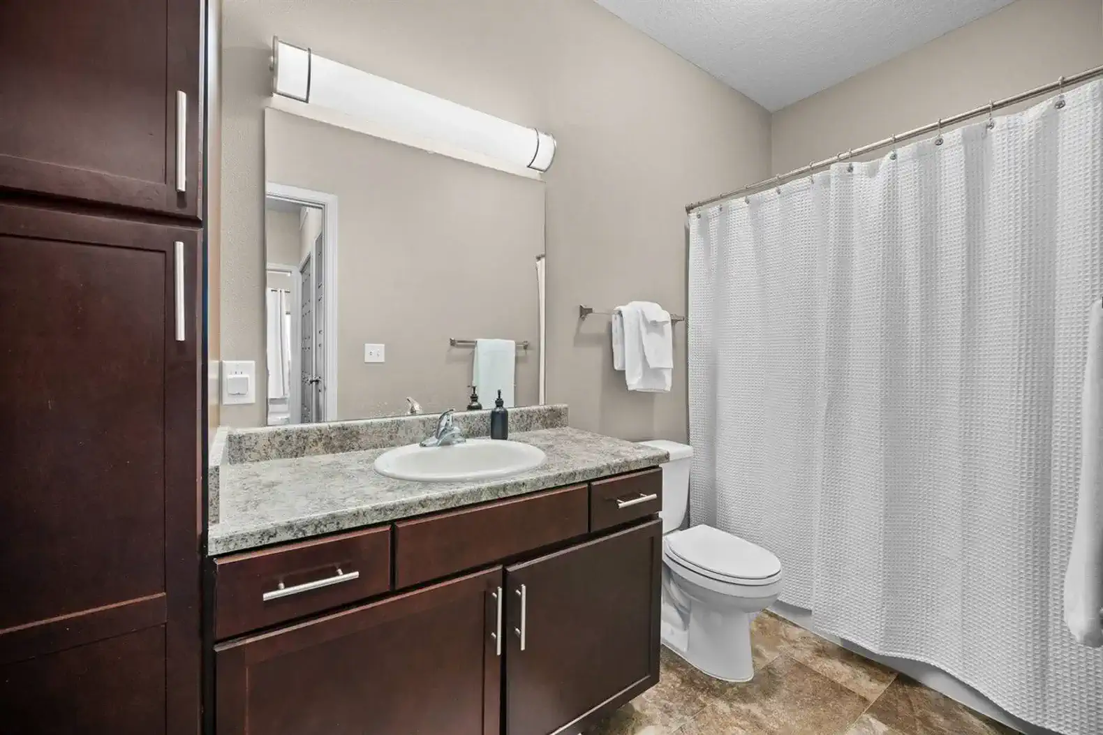 The bathroom has plenty of storage options as well as an adjustable handheld shower head.