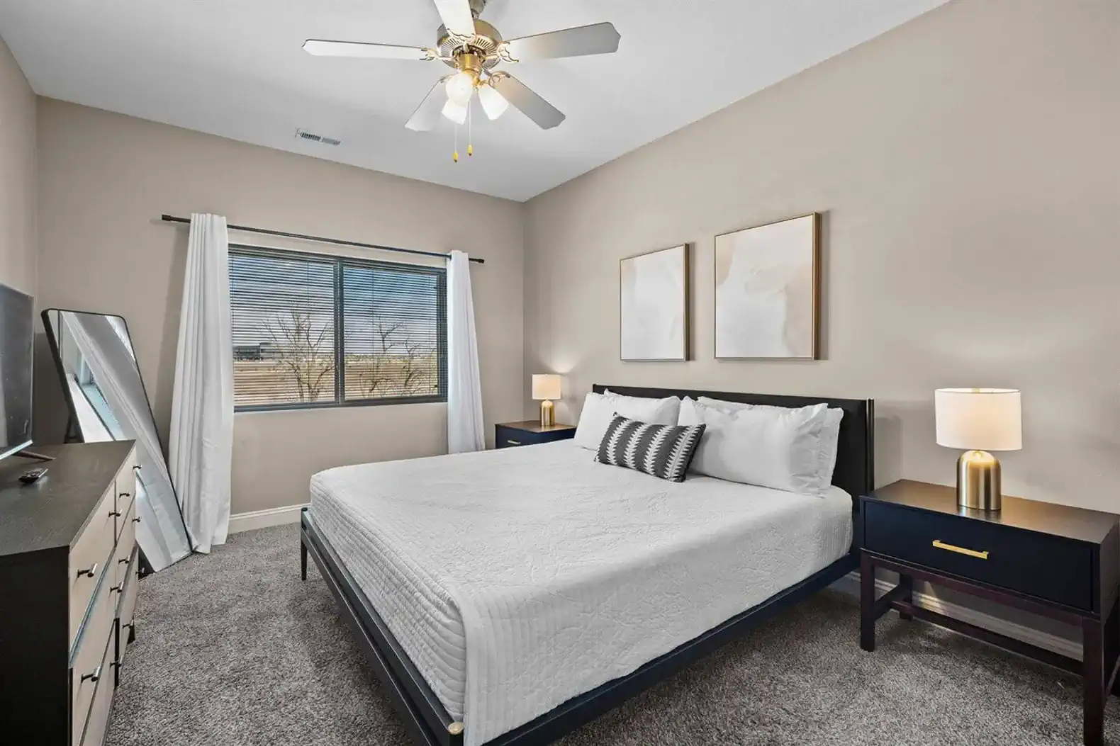 Calm, well-appointed bedroom with a comfortable king-sized bed, fresh linens, smart TV, bedside lighting, a ceiling fan, and room-darkening curtains—designed for restful nights and an easy wind-down after a full day.