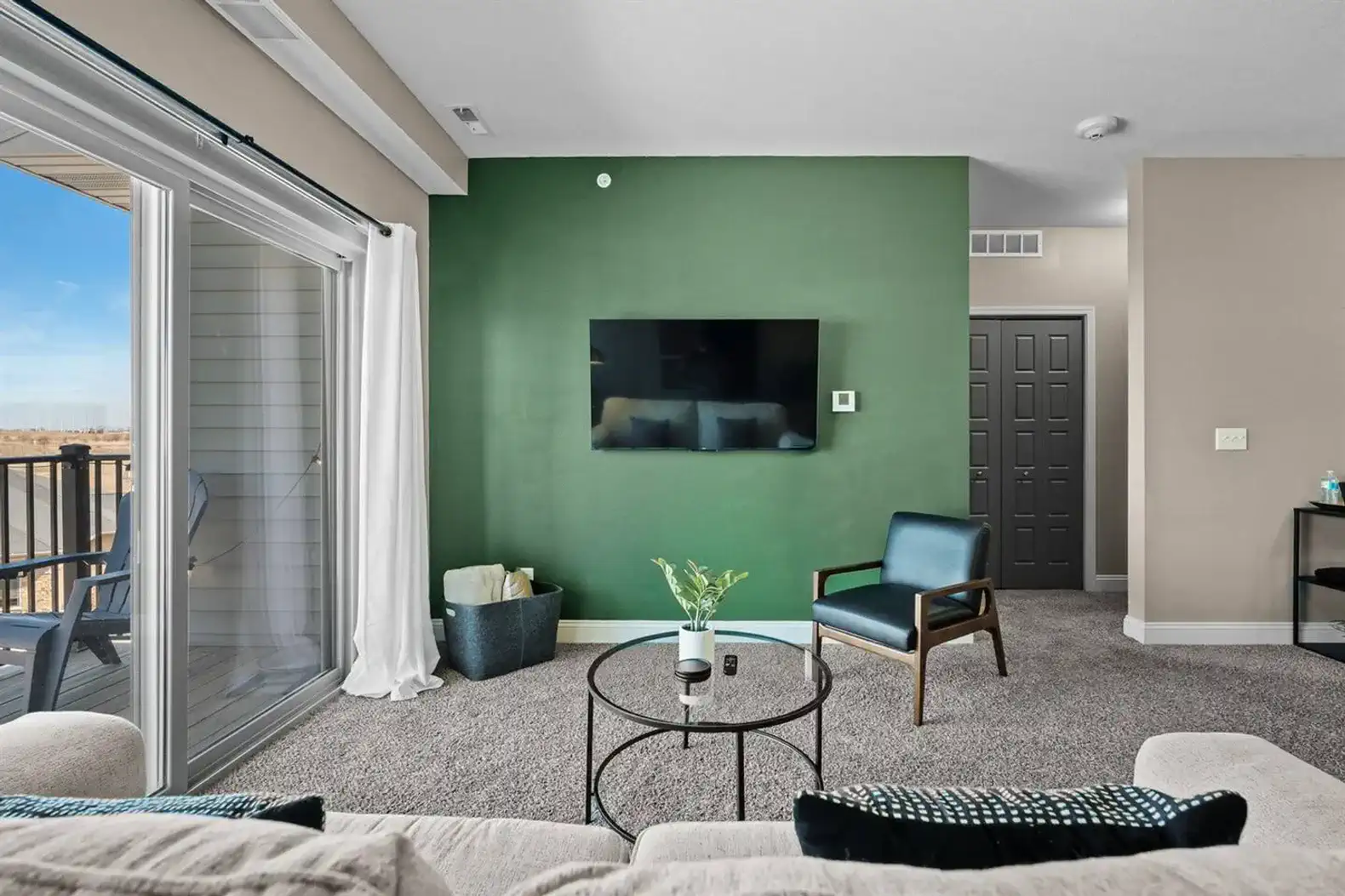Bright, comfortable living room with a wall-mounted TV, cozy seating, and direct access to the private balcony. Located on the top floor, so there are no neighbors above—perfect for a quieter, more relaxed stay.