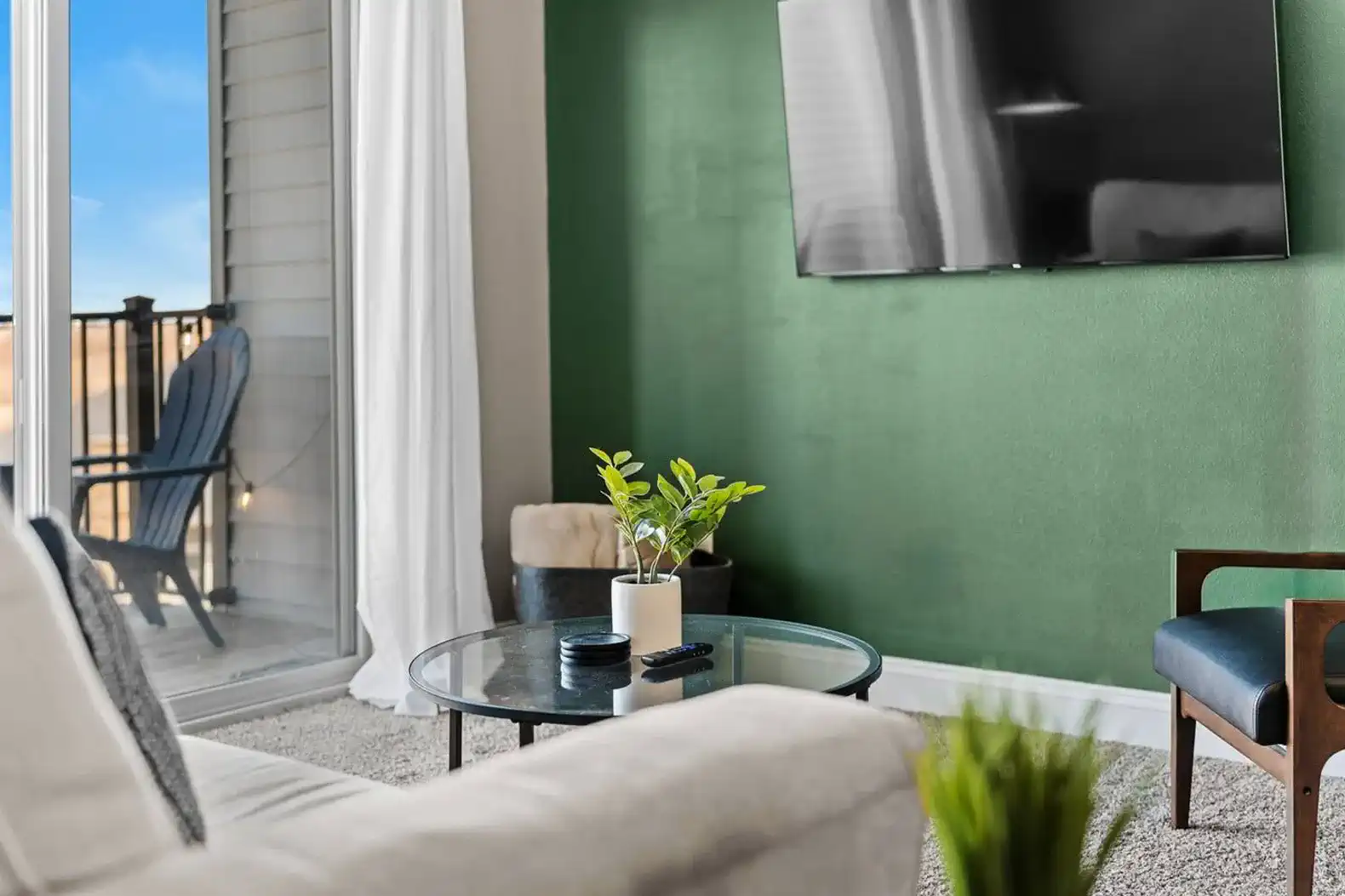 Relax in the cozy living area with a wall-mounted TV, comfortable seating, and natural light. Step out to the private balcony for fresh air—an easy spot to unwind, stream your favorites, or enjoy a quiet moment.