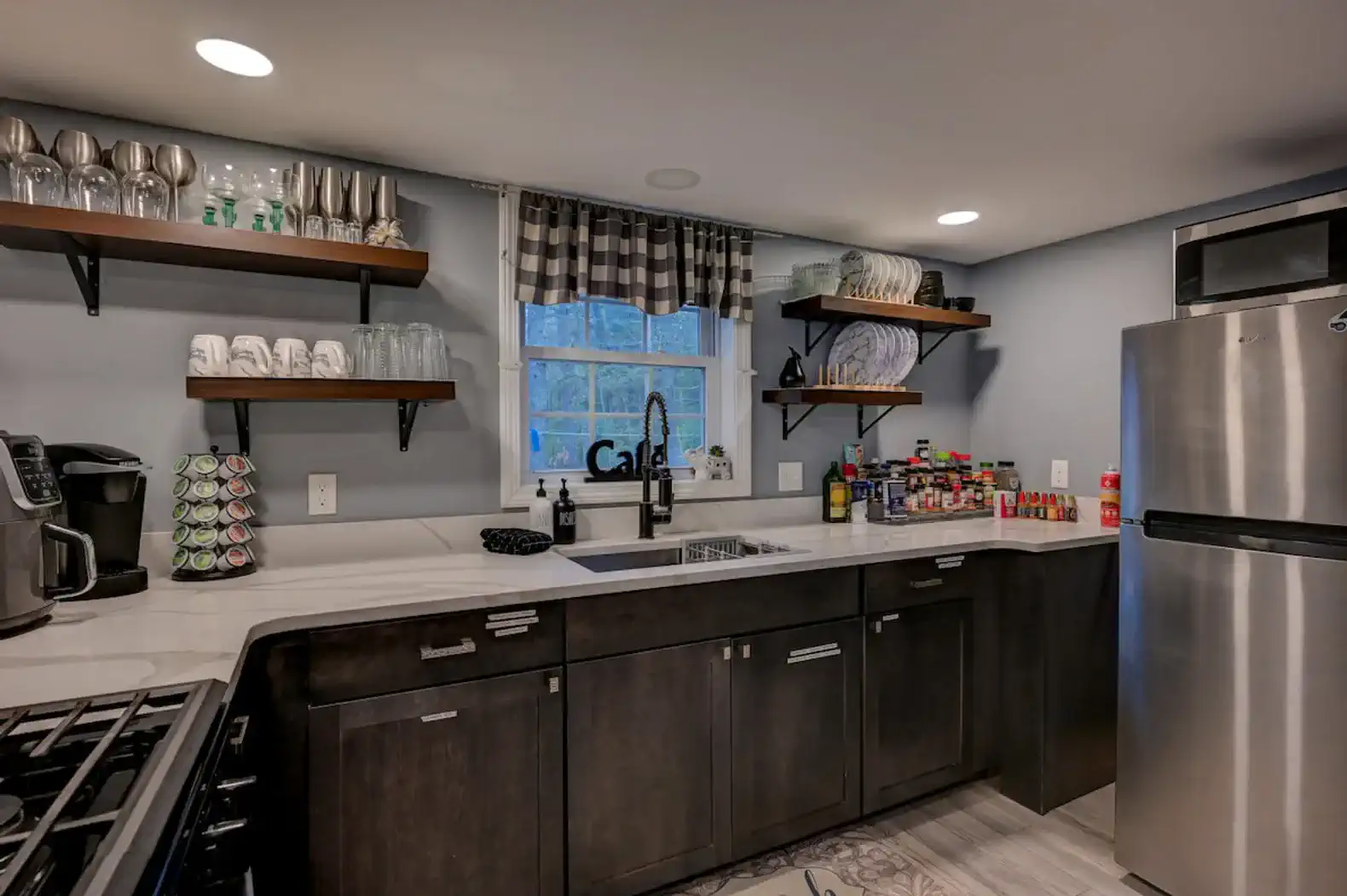 Modern kitchen with dark cabinets, open shelves, and stainless steel appliances