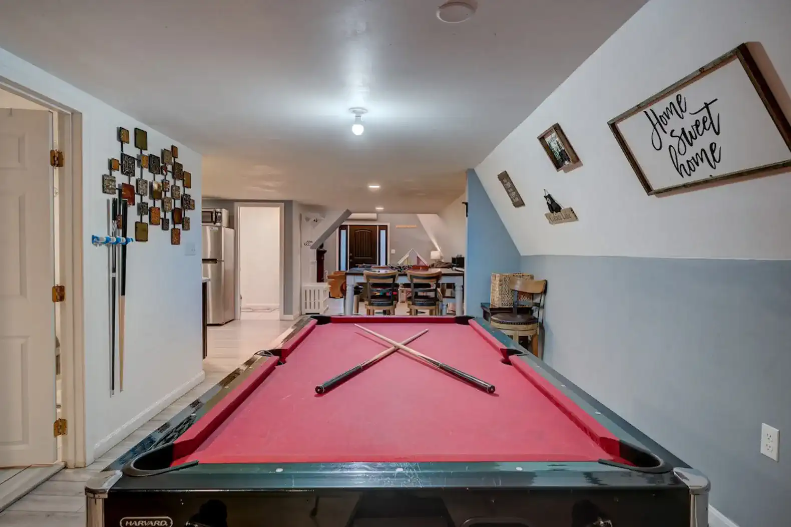 Game room featuring a pool table with cues and a cozy dining area in the background