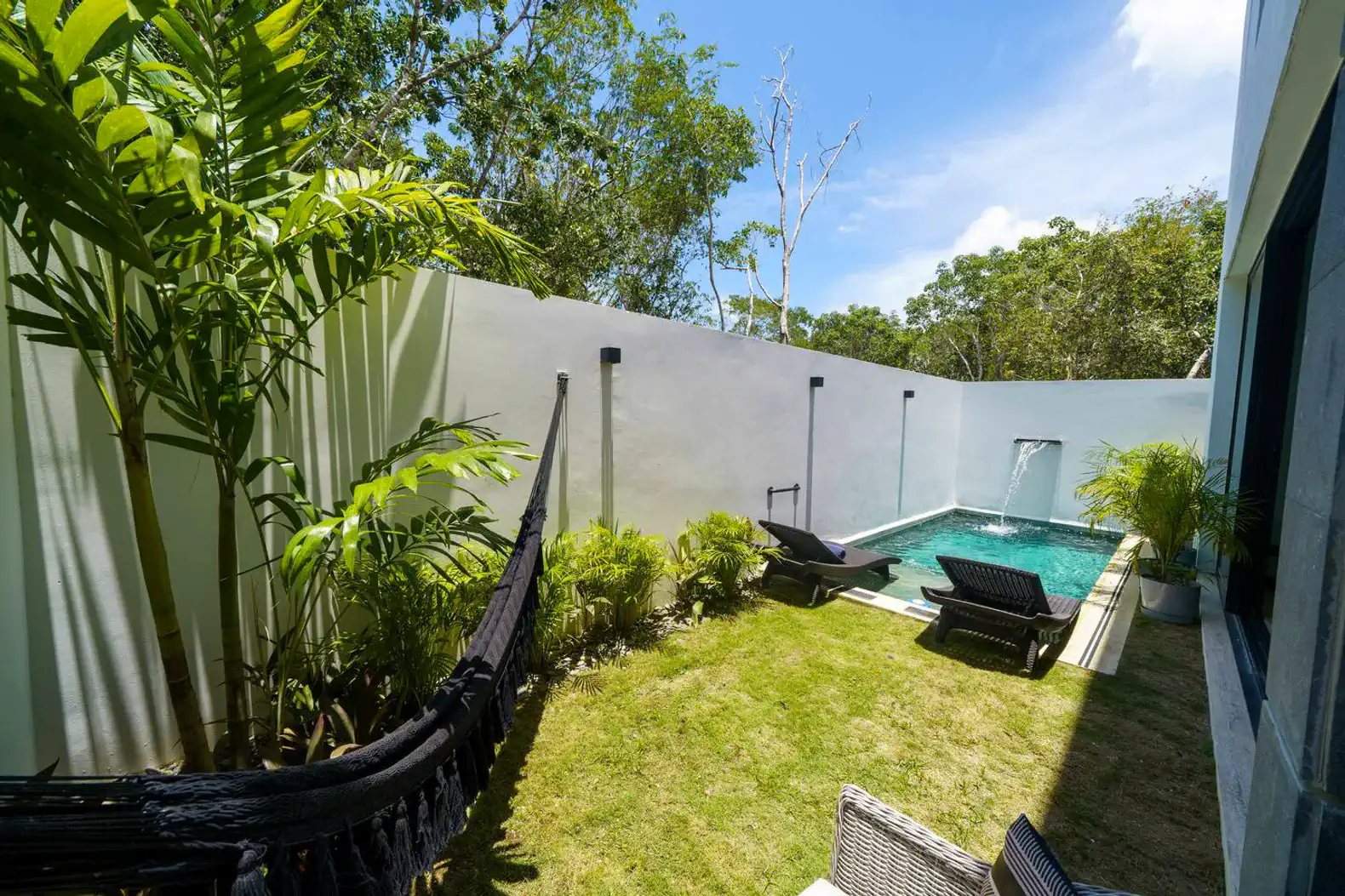 Jardín privado con piscina, hamacas y vegetación exuberante