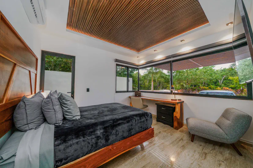Bright modern bedroom with garden views, workspace, and cozy seating