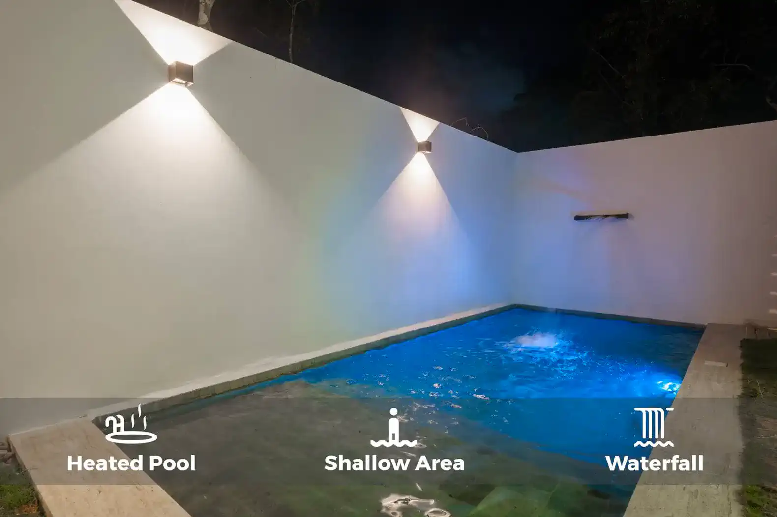 Piscina climatizada con área poco profunda y cascada iluminada