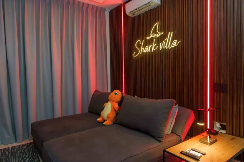 Cozy lounge area with a plush sofa, neon sign, and a cute stuffed toy
