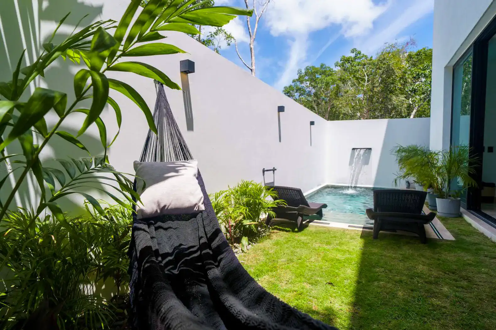 Jardín con hamaca y área de descanso junto a la piscina