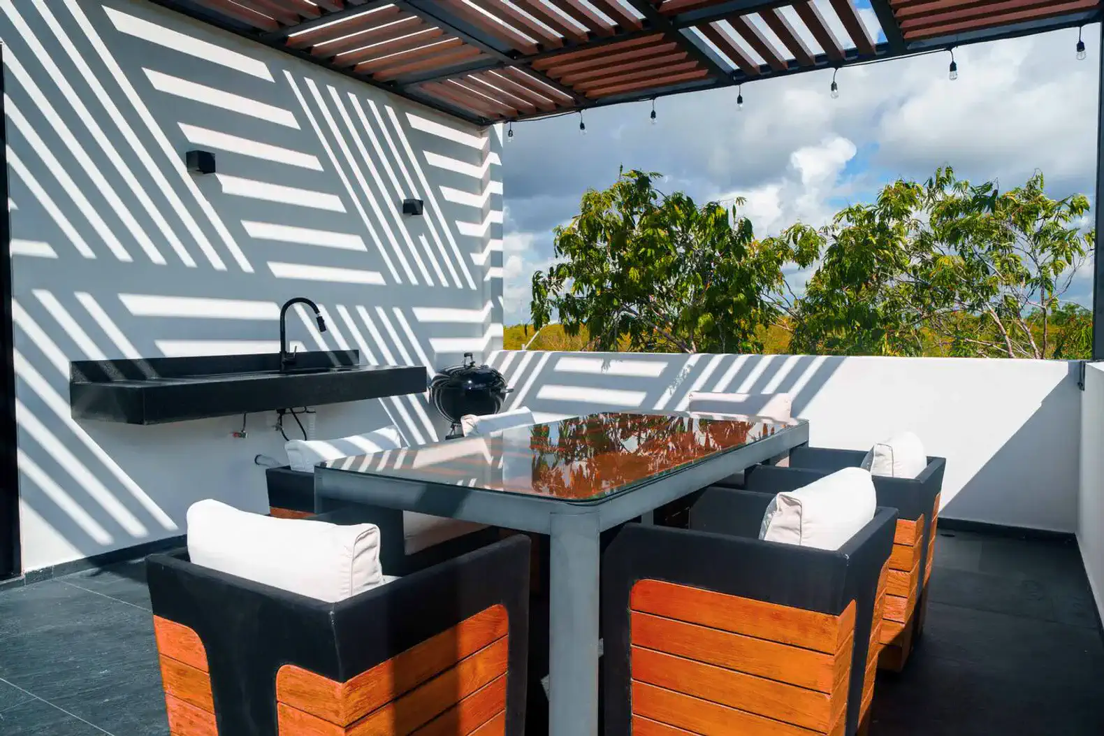 Terraza con mesa de comedor y sillas, vista a la naturaleza y parrilla