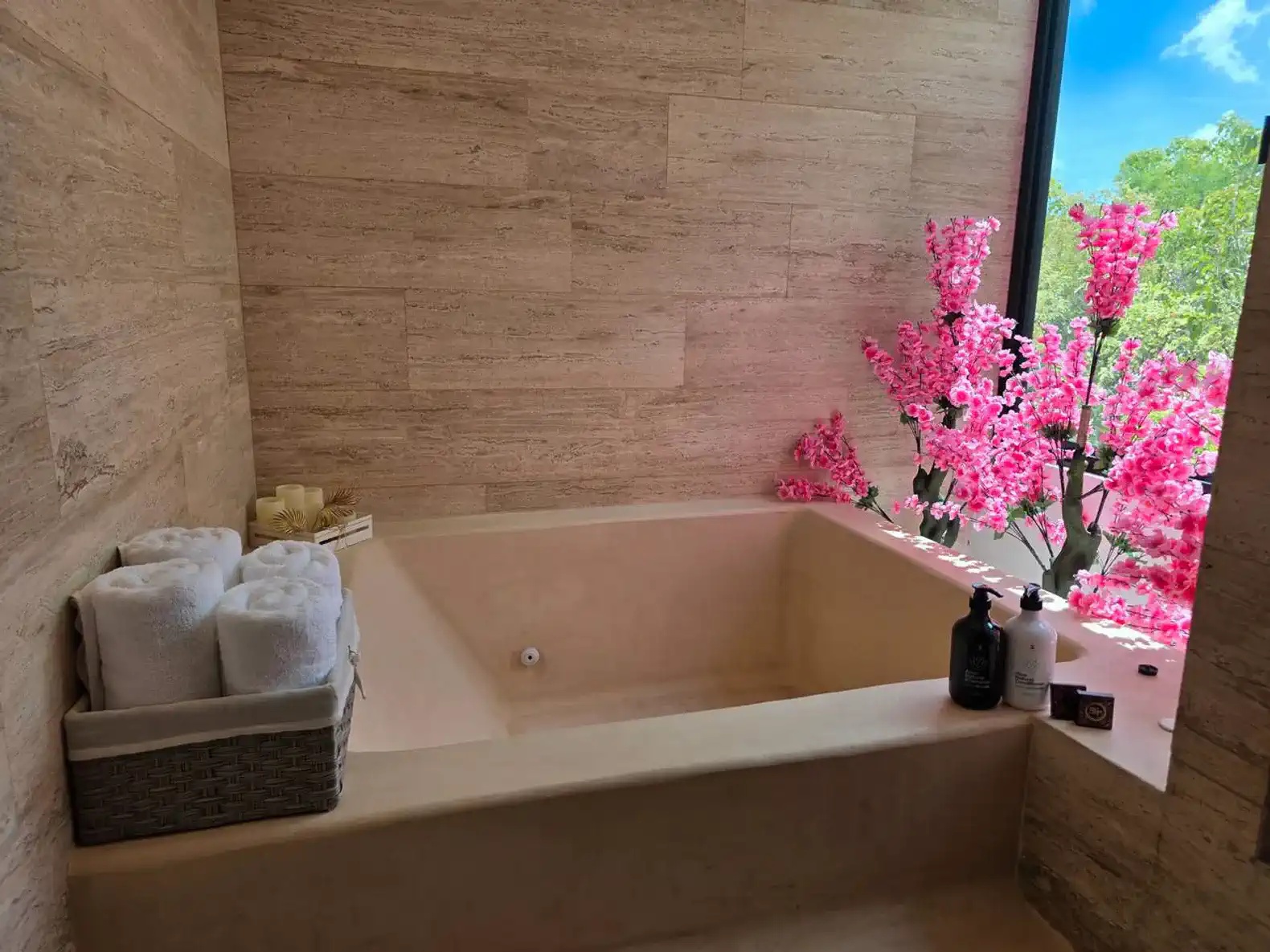 Baño elegante con bañera, toallas blancas y flores rosas decorativas