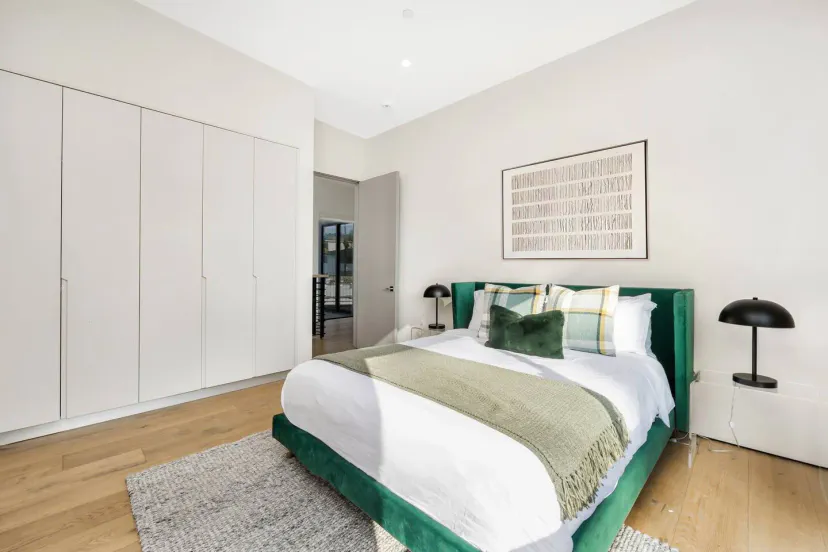 Gemütliches Hauptschlafzimmer mit grünem Bett, moderner Dekoration und viel Stauraum