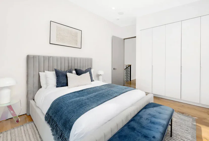 Gemütliches Hauptschlafzimmer mit einem bequemen Bett, dekorativen Kissen und modernem Kleiderschrank