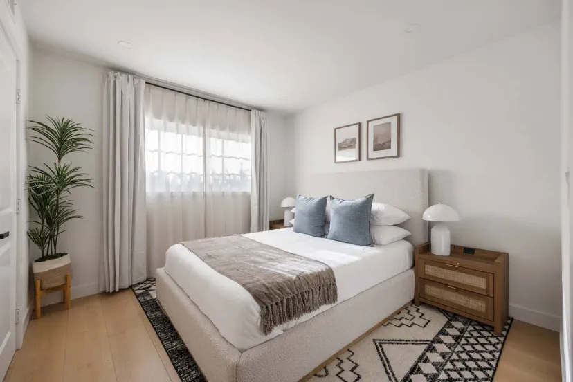 Cozy master bedroom with a large window, decorative pillows, and modern furnishings
