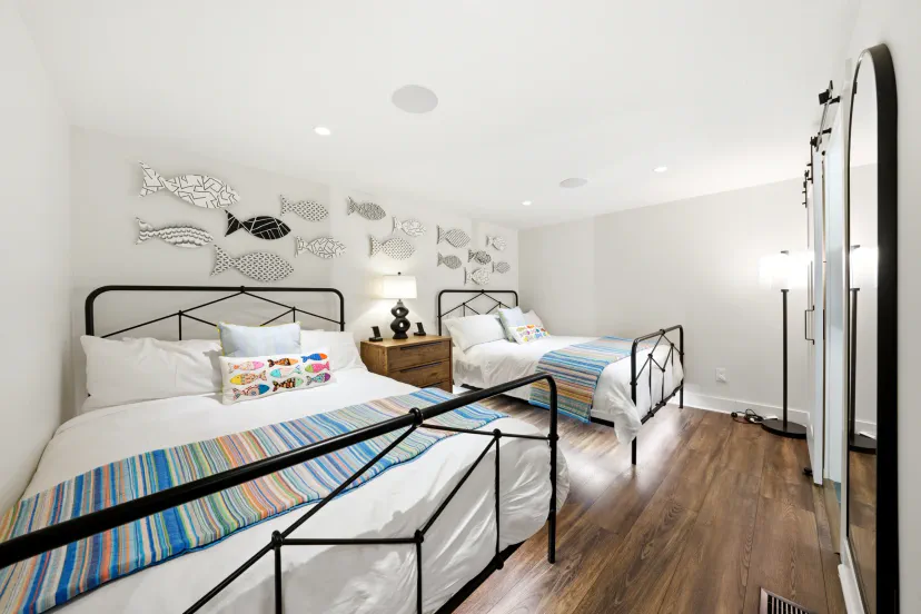 Brillante y aireado dormitorio de invitados con dos camas y decoración de peces coloridos
