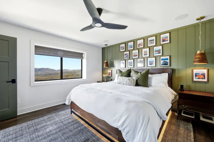Dormitorio king con pared de galería de olivo, ventilador de techo y vistas a las montañas — uno de los 5 hermosamente decorados dormitorios en esta casa de lujo en Tiger, Georgia, junto al Lago Burton.
