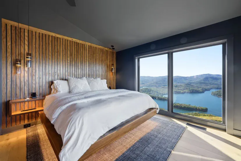 Cama king con pared de acento de listones de madera y vistas directas al Lago Burton — despierta con un paisaje panorámico de lago de montaña en este sereno dormitorio de las Montañas Blue Ridge.